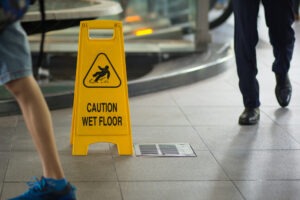 Two Men Walking By A Wet Floor Sign