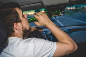 a-driver-drinking-from-a-beer-bottle-while-driving-before-a-dui-accident