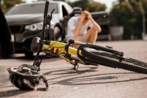 An upset man kneels behind a bicycle. He may hire a Jacksonville bicycle accident lawyer.