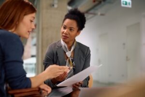 A lawyer sits at her desk with papers in hand and responds to her client’s question of, “Who pays for car damage in Florida no-fault accidents?”