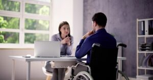 A work accident lawyer explaining to an injured client in a wheelchair how long he has to file a lawsuit for his work accident.